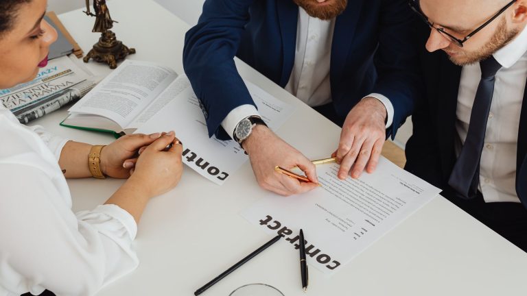 Choosing Counsel and Strategy for Cross-Border Business Disputes Lawyers review the terms of a contract together at a white desk, illustrating choosing Counsel and Strategy for Cross-Border Business Disputes
